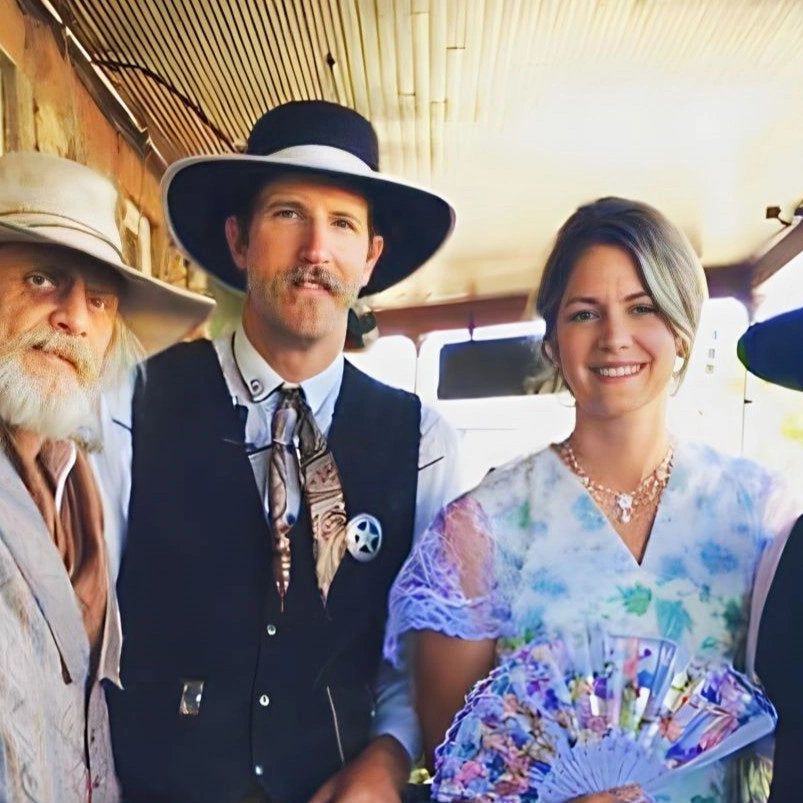 Group of four individuals in a vintage train setting, each wearing distinctive custom western hats, embodying a blend of traditional and contemporary western fashion.