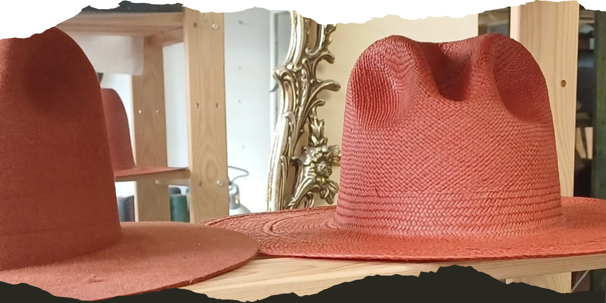 Two handcrafted red hats, one felt and one straw, displayed on wooden shelves with a decorative gold mirror in the background, showcasing the craftsmanship of Agnoulita Hats.