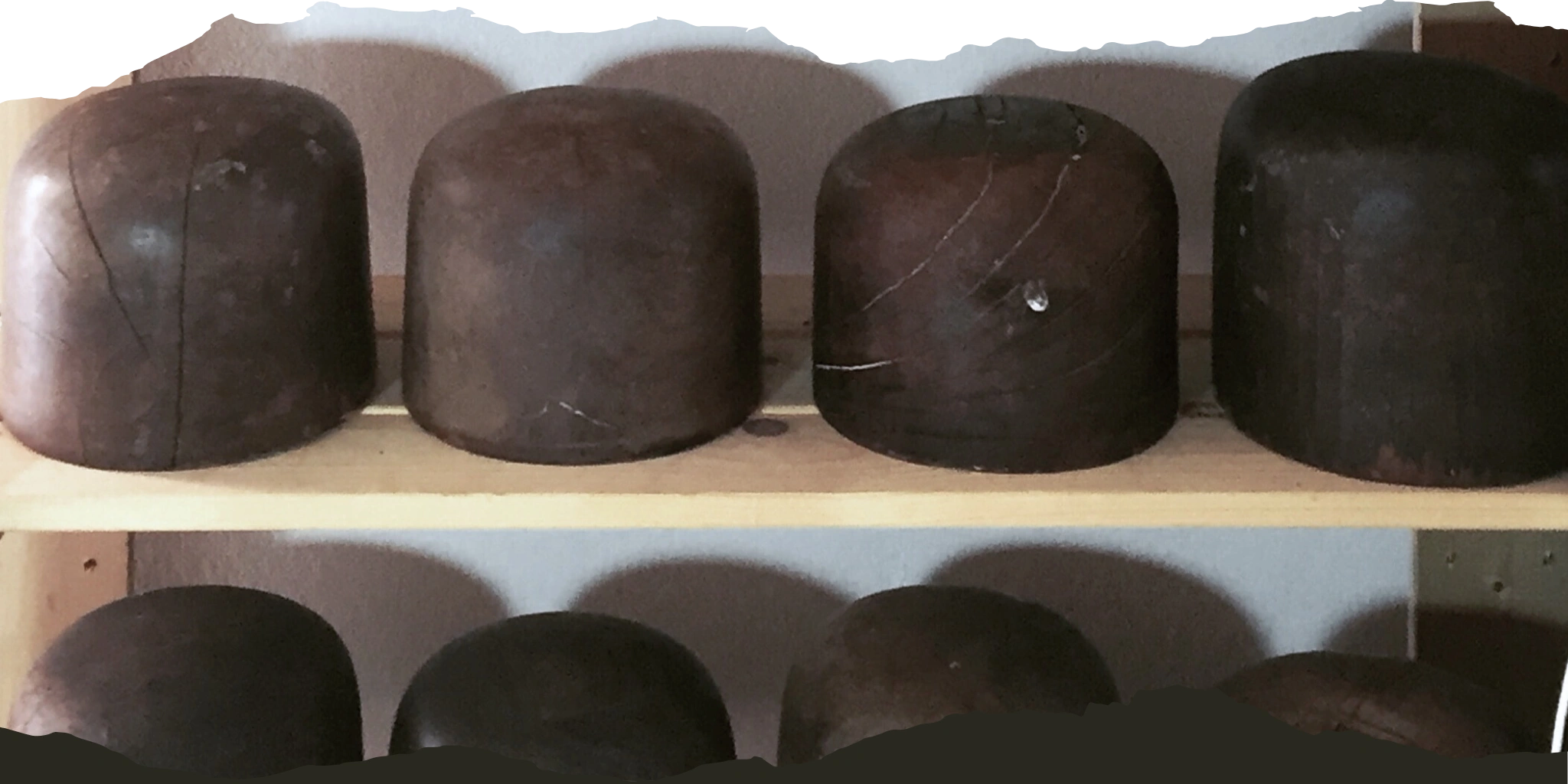 Wooden hat blocks arranged on shelves, showcasing the tools and techniques used in expert hat repair and restoration services.