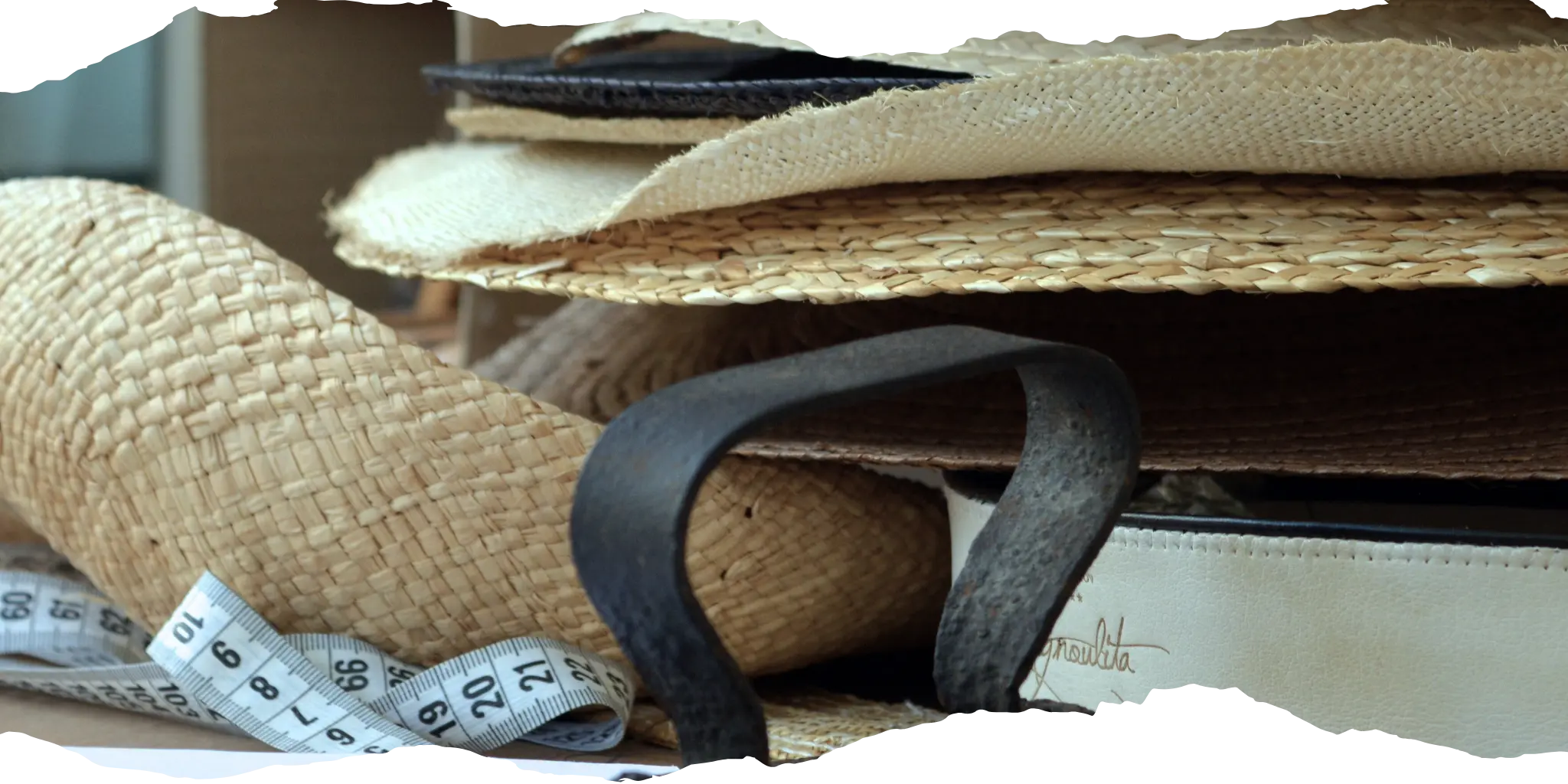 Assortment of straw felt hats in various colors and styles on a workbench, showcasing the customization and craftsmanship of Agnoulita Hats.